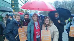 Caritaspräsidentin Eva Welskop-Deffaa neben Sanna Zachej, Referentin der Arbeitsstelle Rechtliche Betreuung DCV, SkF und SKM mit Ulrike Gödeke, SKM Freiburg und Salvatore Heber SKFM Speyer unter Schirm auf der Protestaktion
