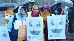 Protestierende der Berliner Betreuungsvereine der Caritas halten im Regen Plakate des Aktionsbündnis Vergütung Rechtlicher Betreuung hoch