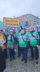 Menschen in einer Protestmenge halten ein Schild hoch mit dem Schriftzug Baustelle